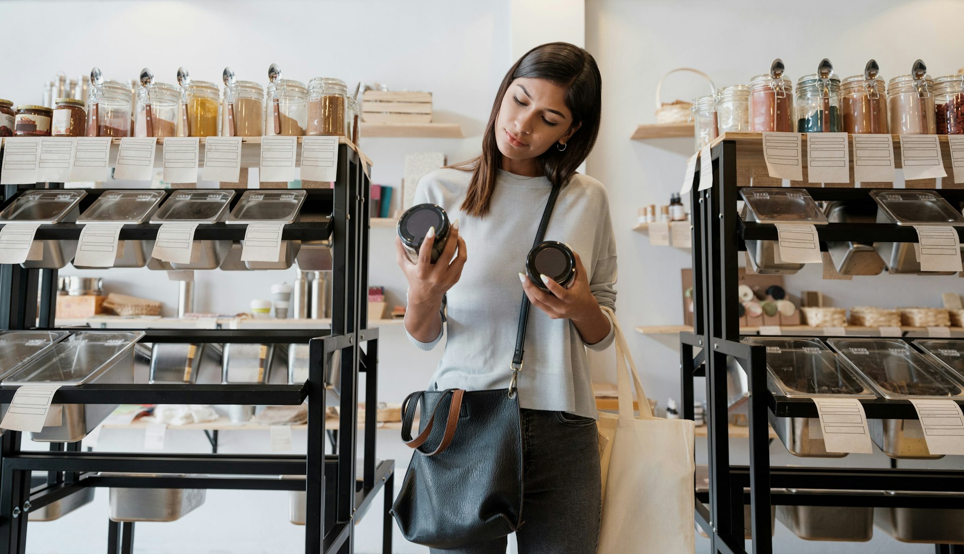 Eine Frau im Supermarkt vergleicht Lebensmittelpreise – eine Anspielung auf die Inflation.