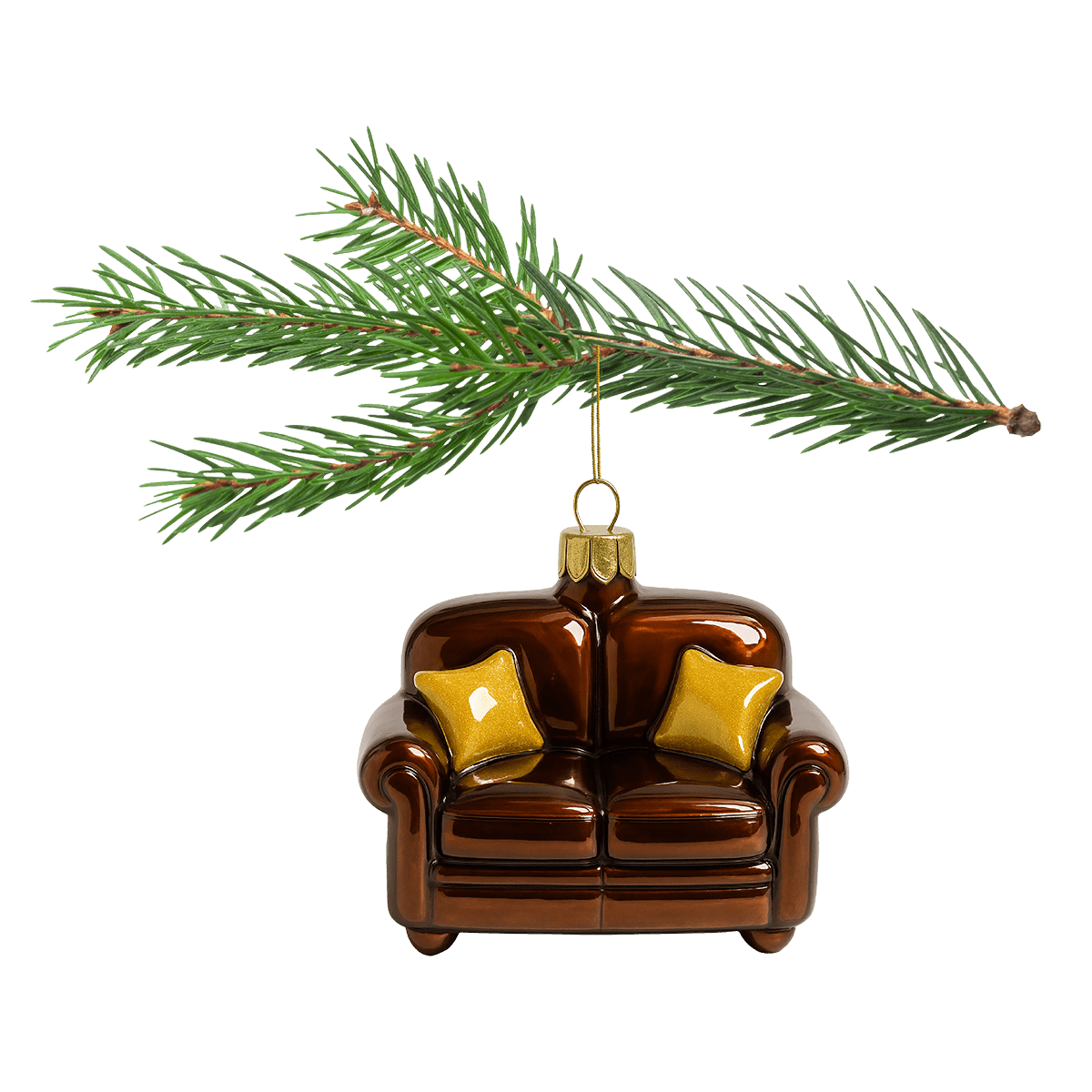 Ein braunes Sofa-Weihnachtsornament mit zwei goldenen Kissen hängt an einem grünen Tannenzweig.