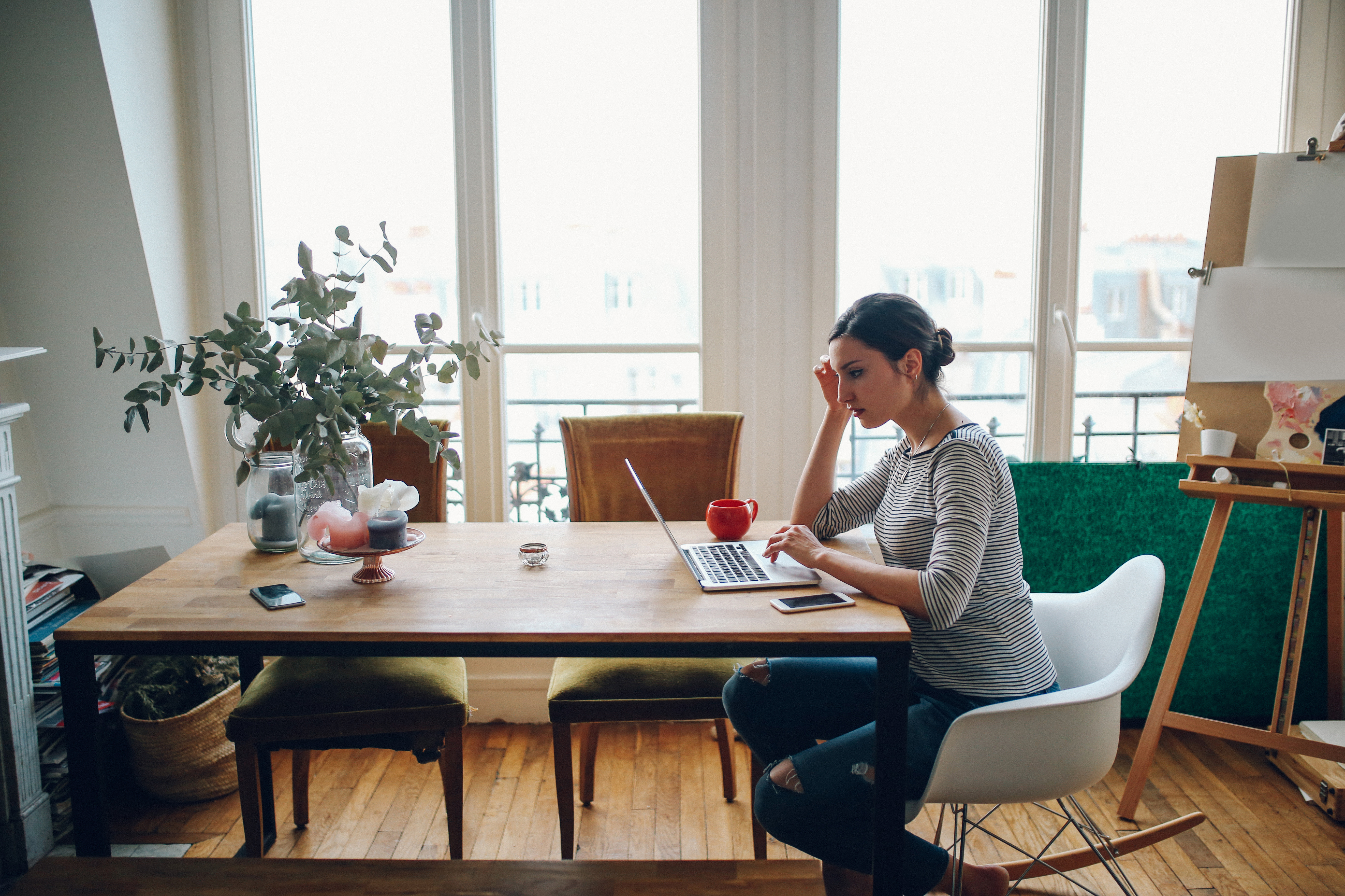 Frau informiert sich mit Laptop am Küchentisch über Mietpreis