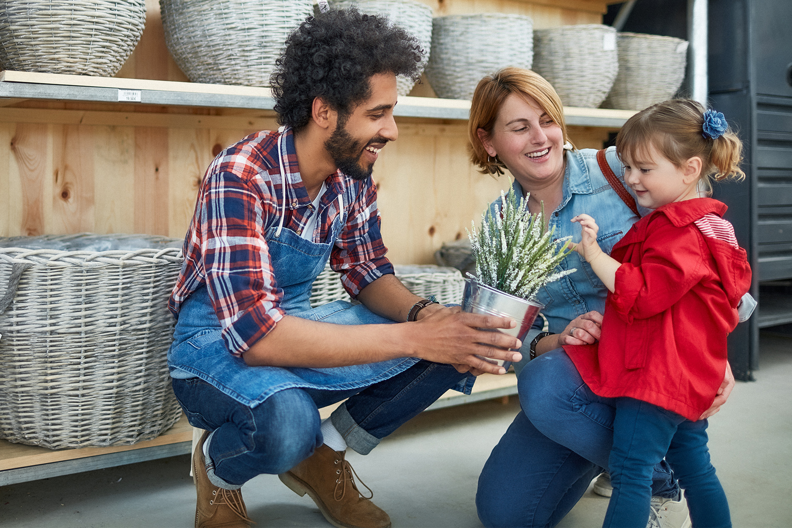 Studentischer Verkäufer zeigt Kundin mit Kind eine Pflanze