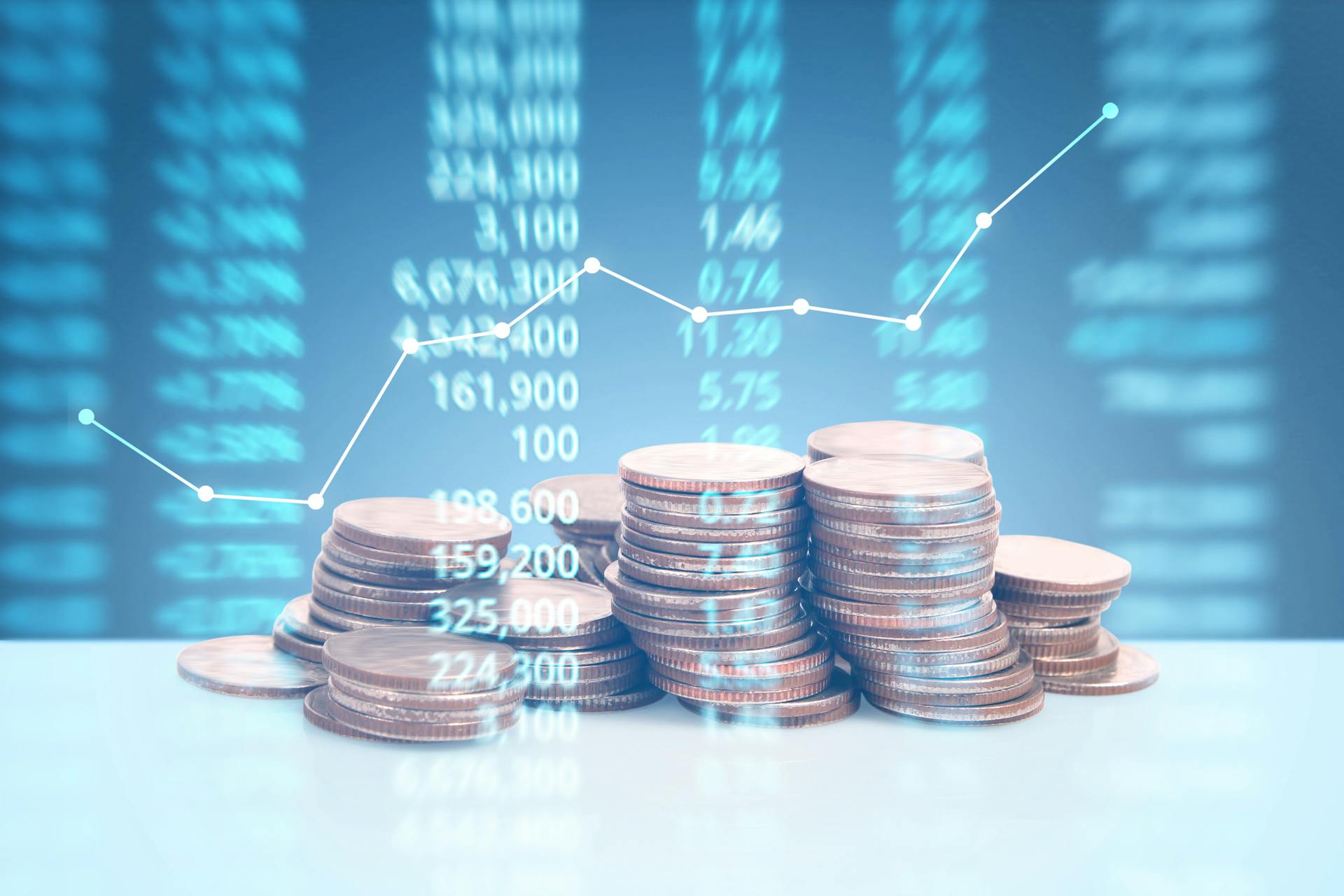 Ein Haufen Geldmünzen vor einem Graphen von Aktienkursen symbolisiert die Konjunktur.