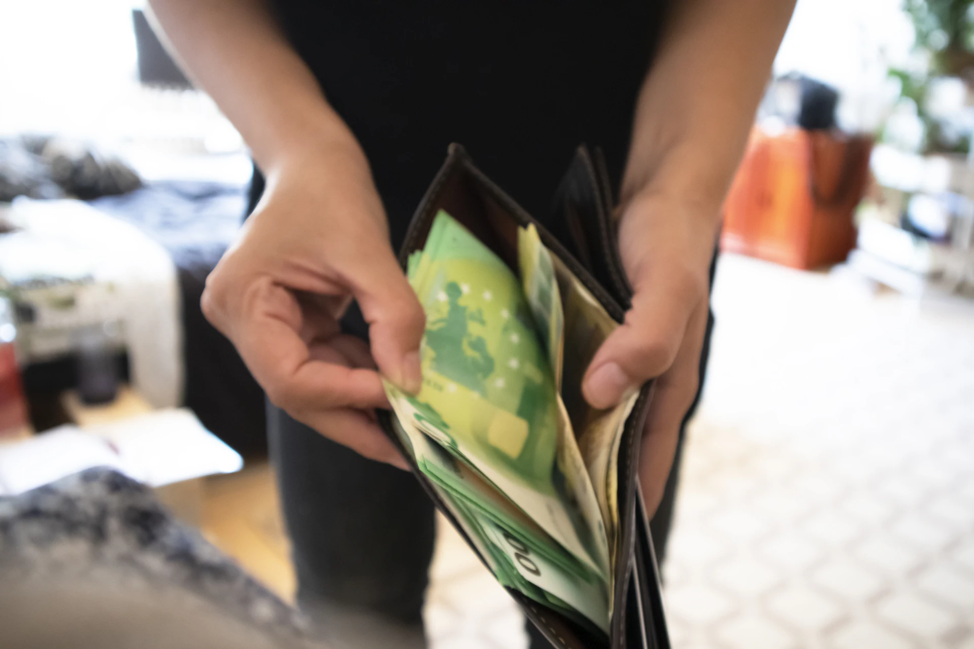 Mensch zeigt volles Geldbörserl mit vielen Euro-Scheinen.