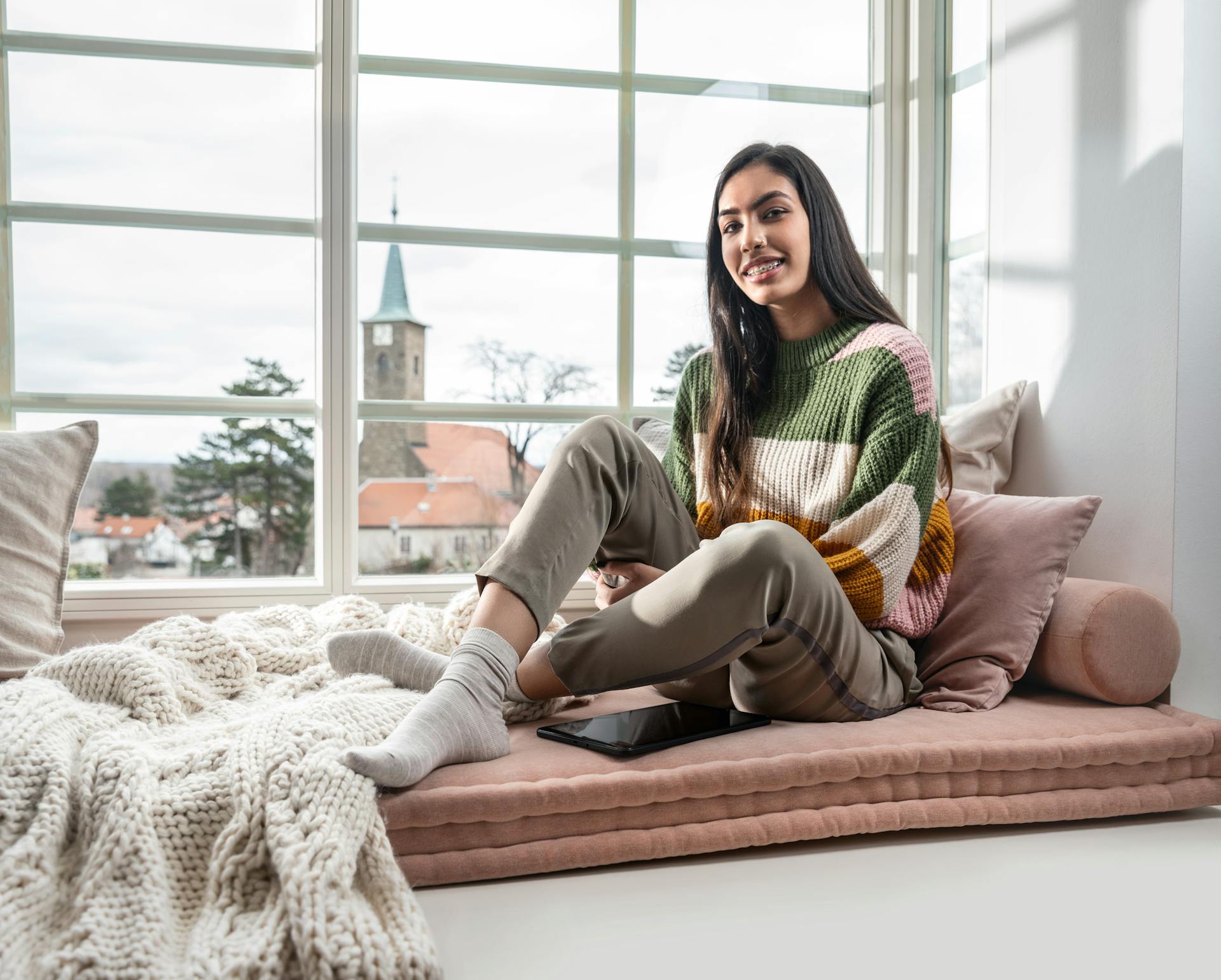 Ein Teenager sitzt im Winter auf kuscheliger Fensterbank.