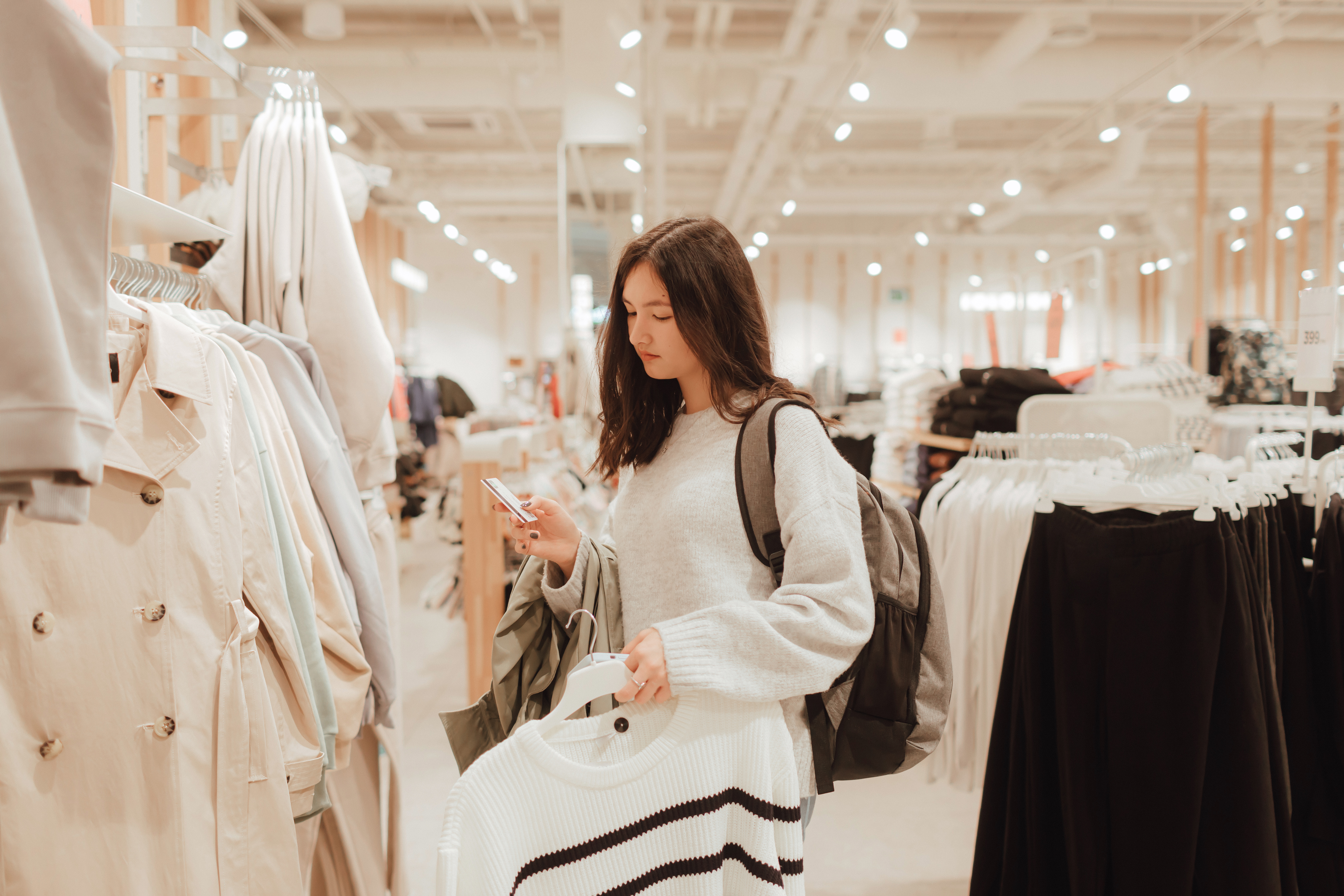 Junge Frau hält eine Kreditkarte in der Hand und steht beim Einkaufen in einem Geschäft.