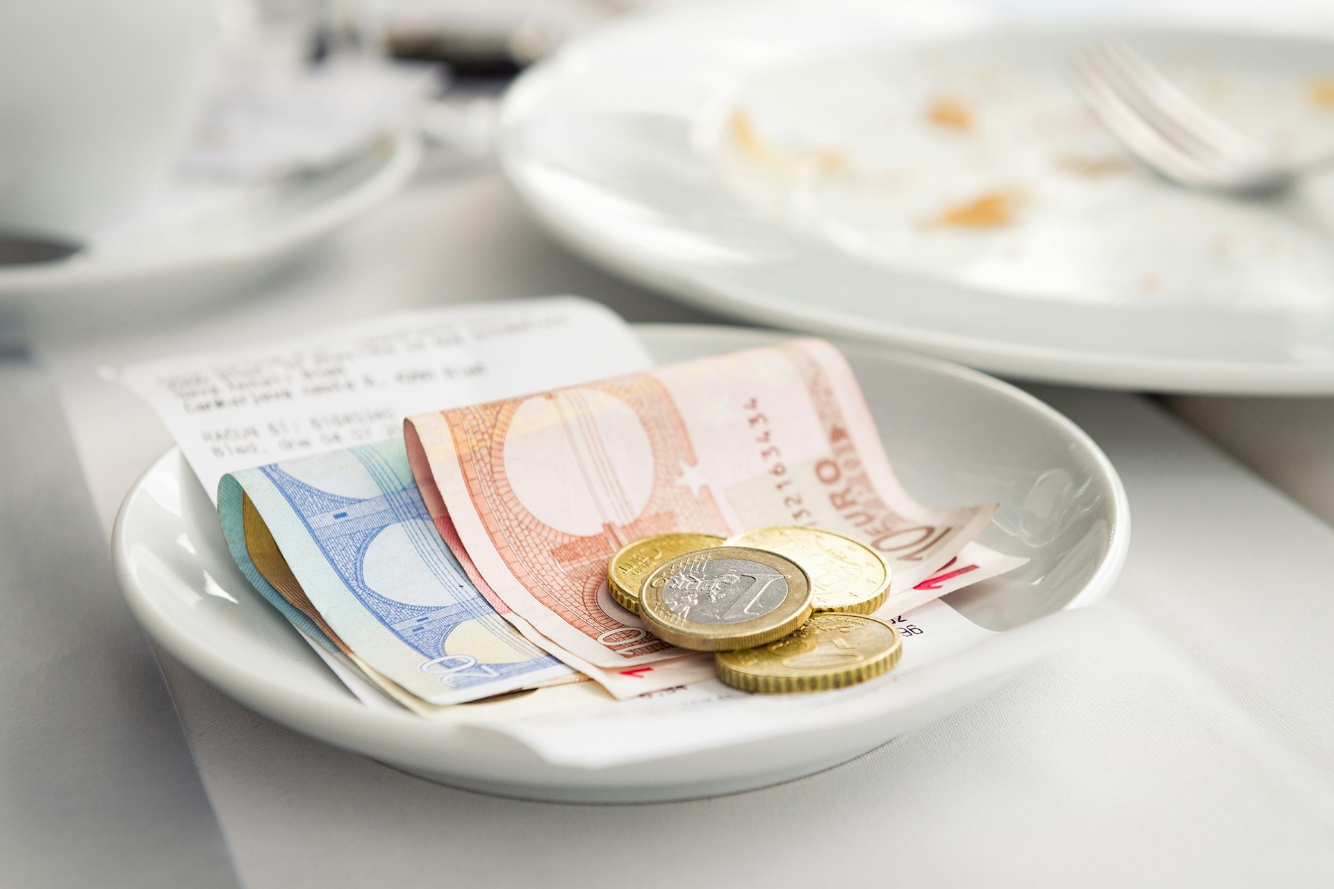 Bargeld auf einem Teller – ein Hinweis auf alternative Bezahlsysteme, die über Geldscheine und Münzen hinausgehen.