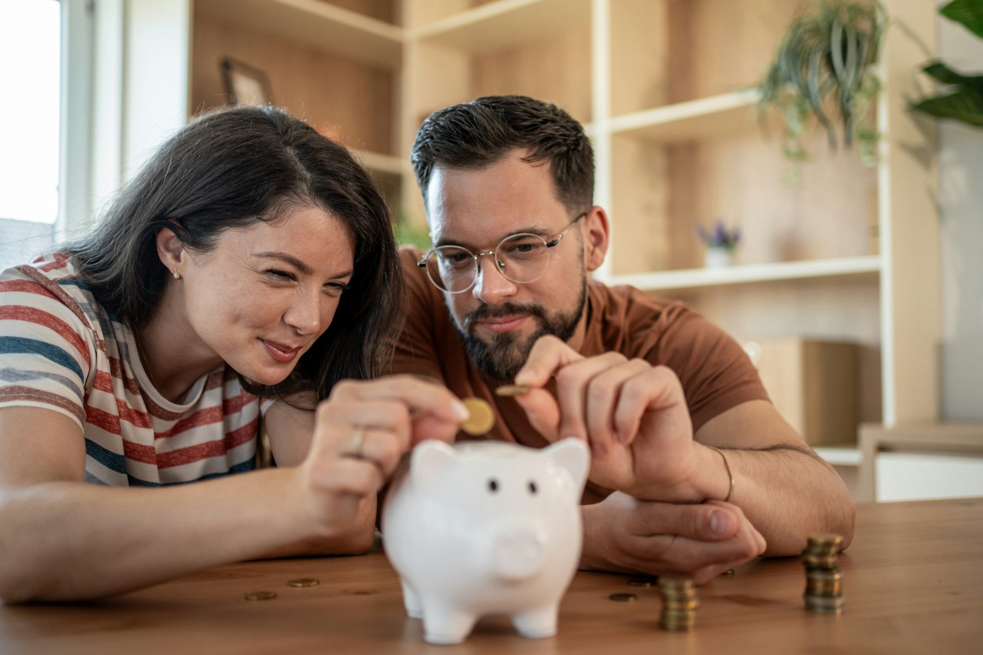 Pärchen wirft gemeinsam Geld in ein Sparschwein am Weltspartag.