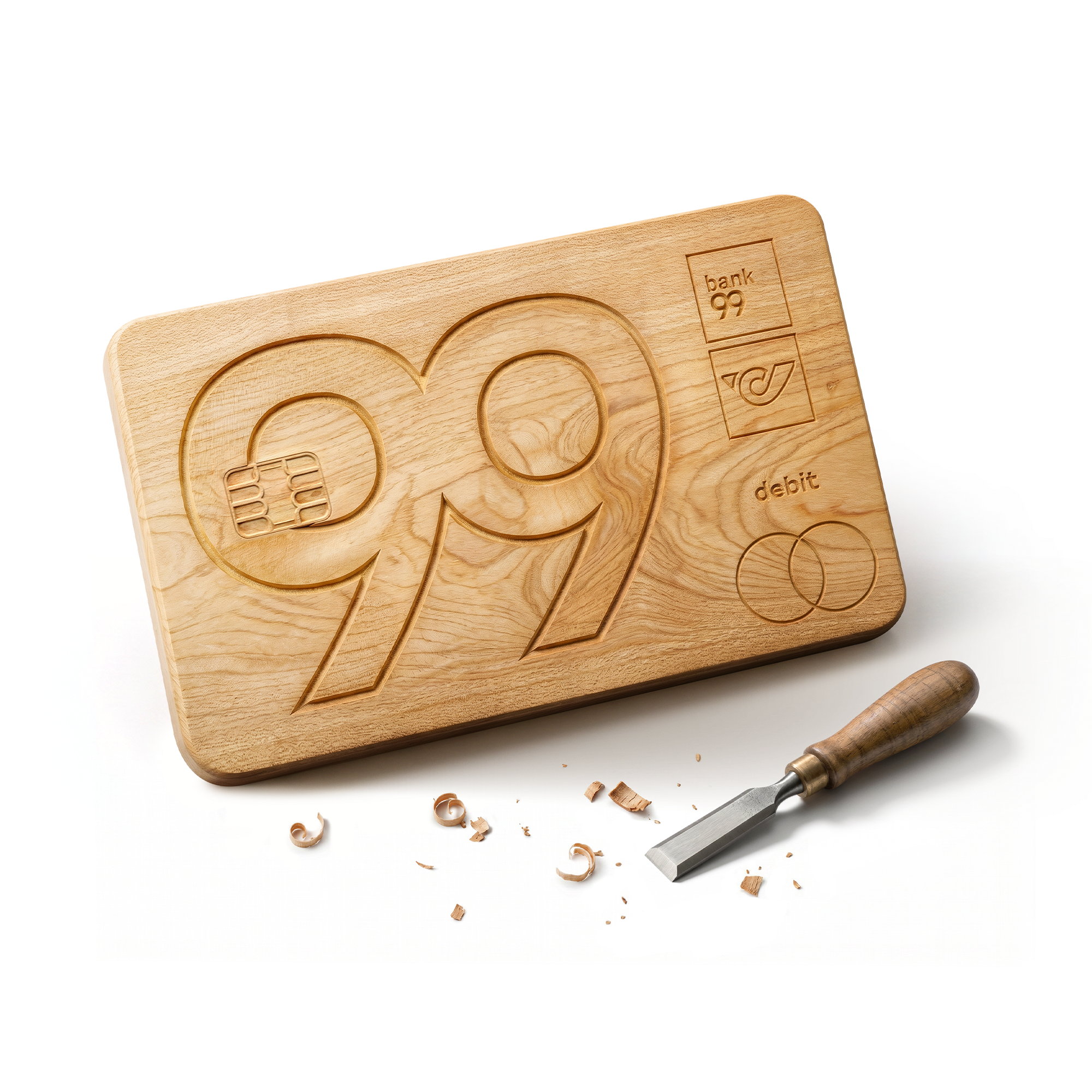 bank99 Debitkarte aus Holz mit eingravierter Zahl 99, daneben ein Stechbeitel und Holzspäne.